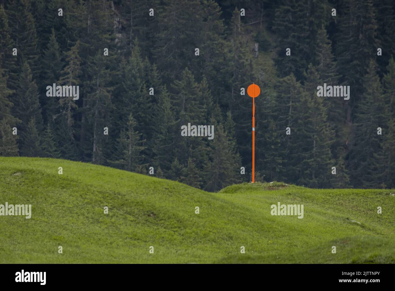 Orange sign with round plates to denote gas pipe buried under the green grass in austrian countryside. Stock Photo
