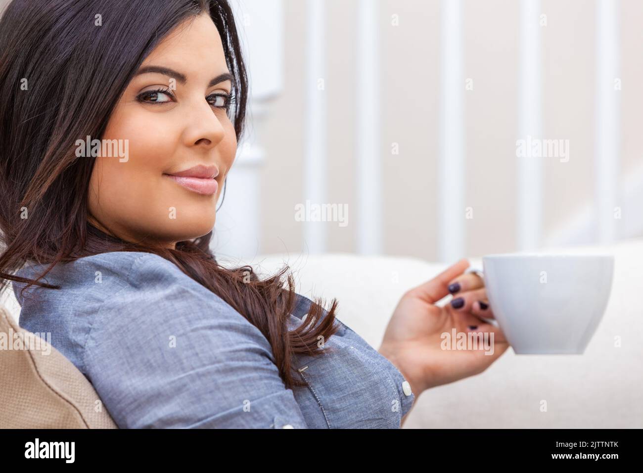 Portrait of a beautiful young Latina Hispanic woman at home relaxing with a cup of tea or coffee. Stock Photo