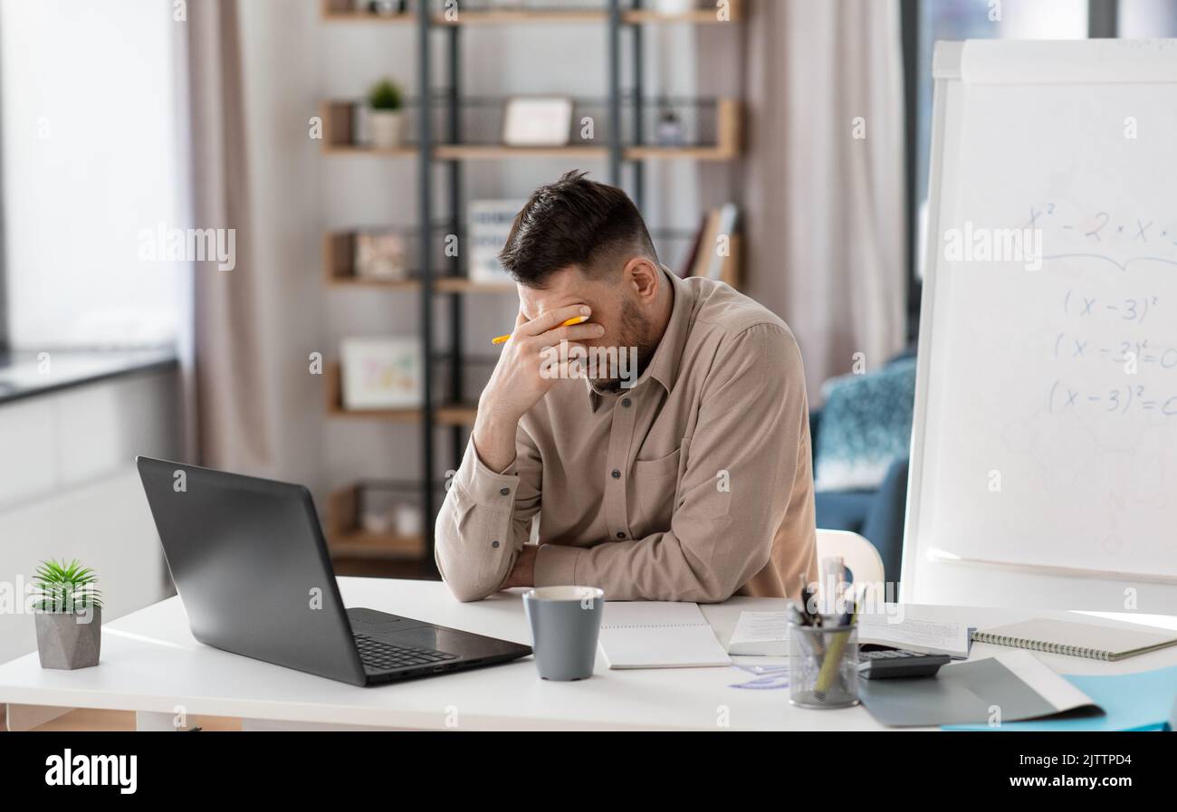 tired male teacher with laptop working at home Stock Photo