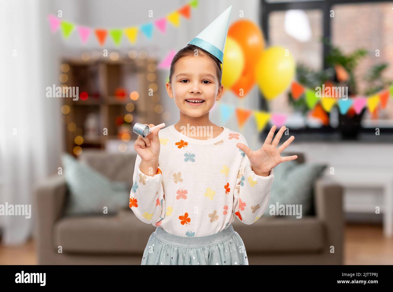 smiling girl in birthday party hat with blower Stock Photo - Alamy
