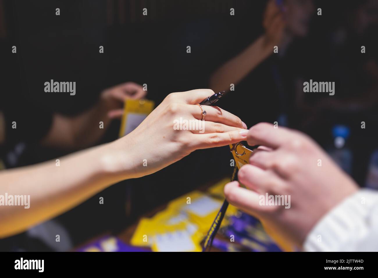 Process of checking in on a conference congress forum event, the registration desk table, visitors and attendees receiving a name badge and entrance w Stock Photo