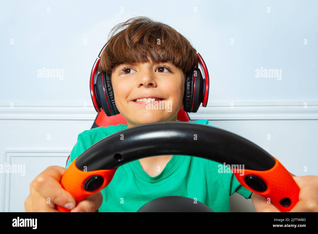 Smiling happy gamer boy with steering wheel play race game Stock Photo