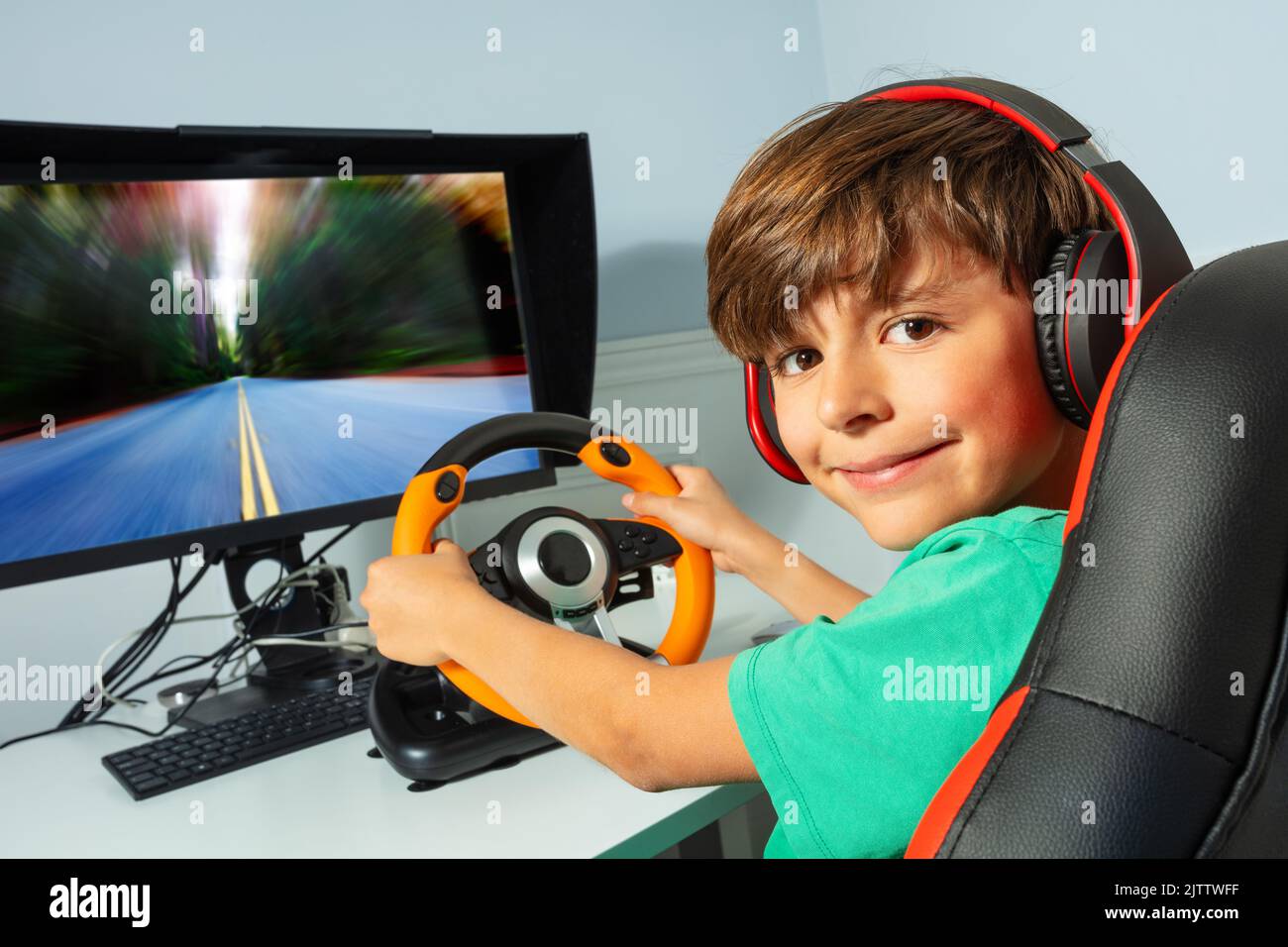 Smiling gamer teen boy hands on steering wheel play race game Stock Photo
