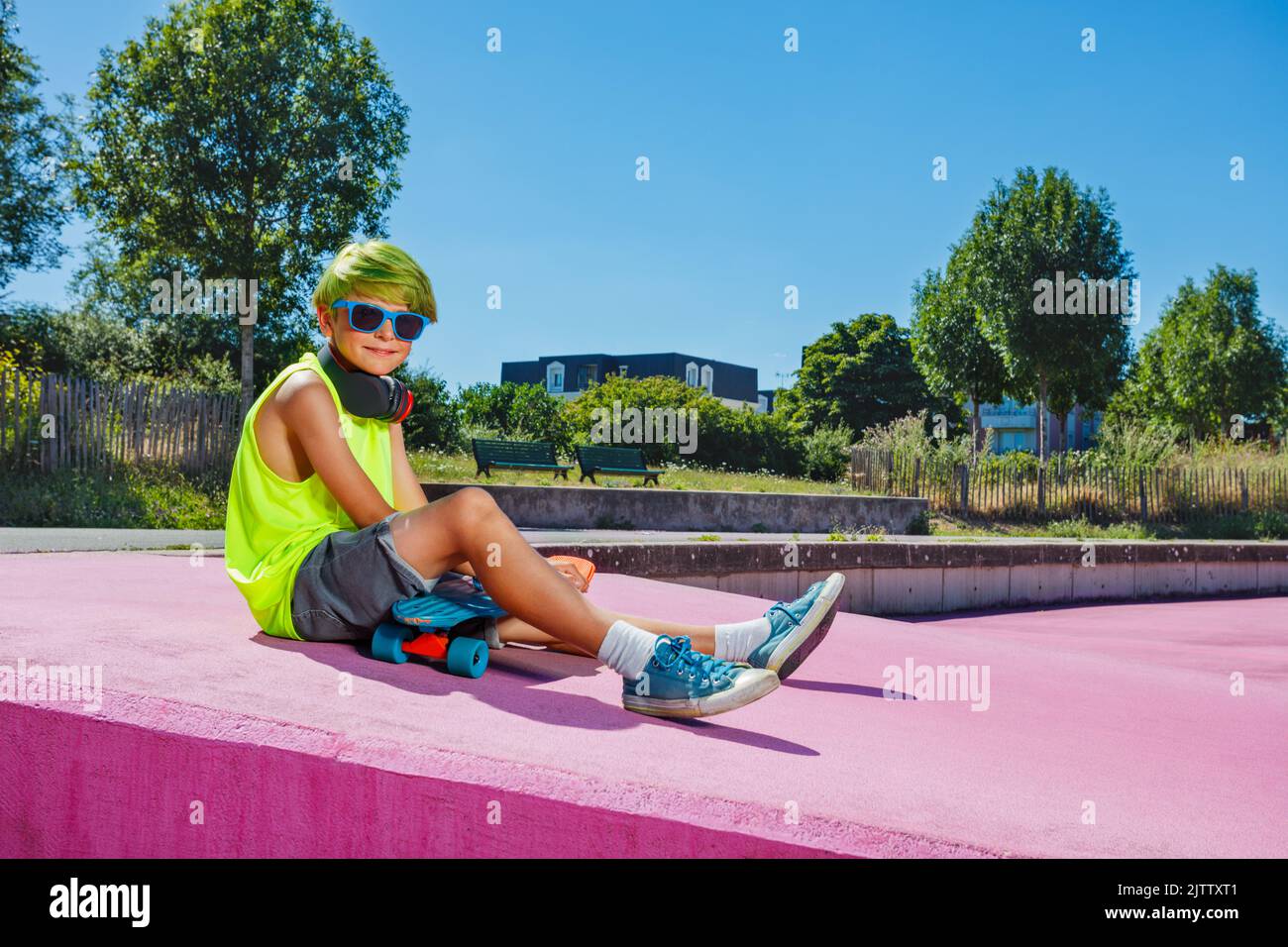 Handsome young preteen boy with green hair sit on ramp Stock Photo