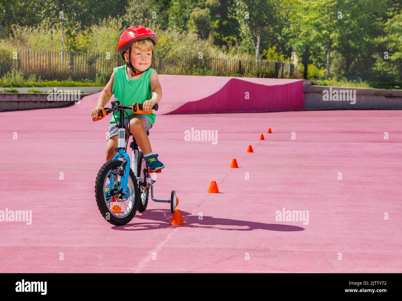 Boy ride small bicycle with learning wheels around orange cones Stock Photo