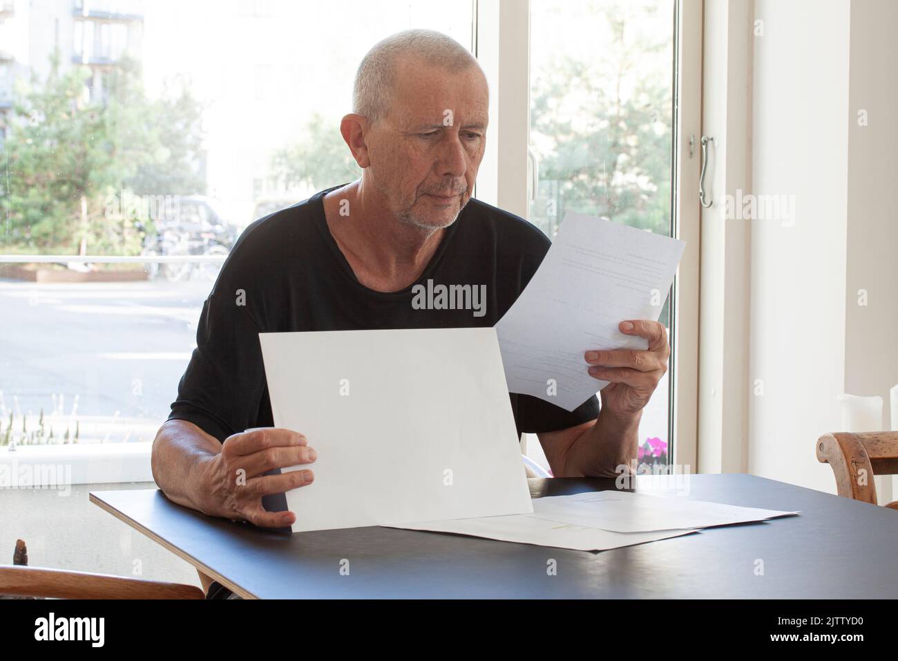Man reading paper documents while sitting at table. Stock Photo