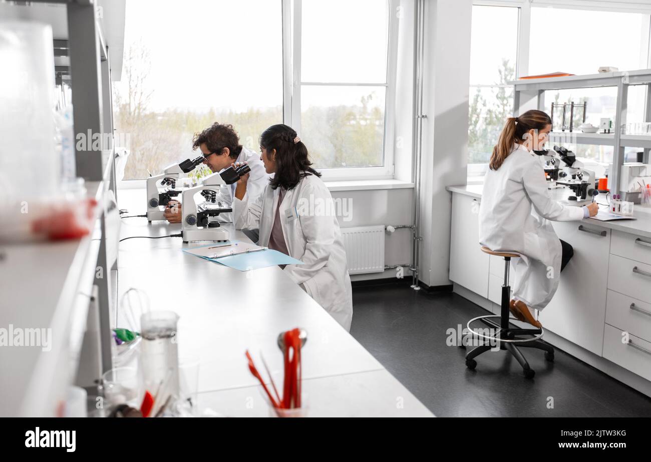 scientists with microscopes working in laboratory Stock Photo