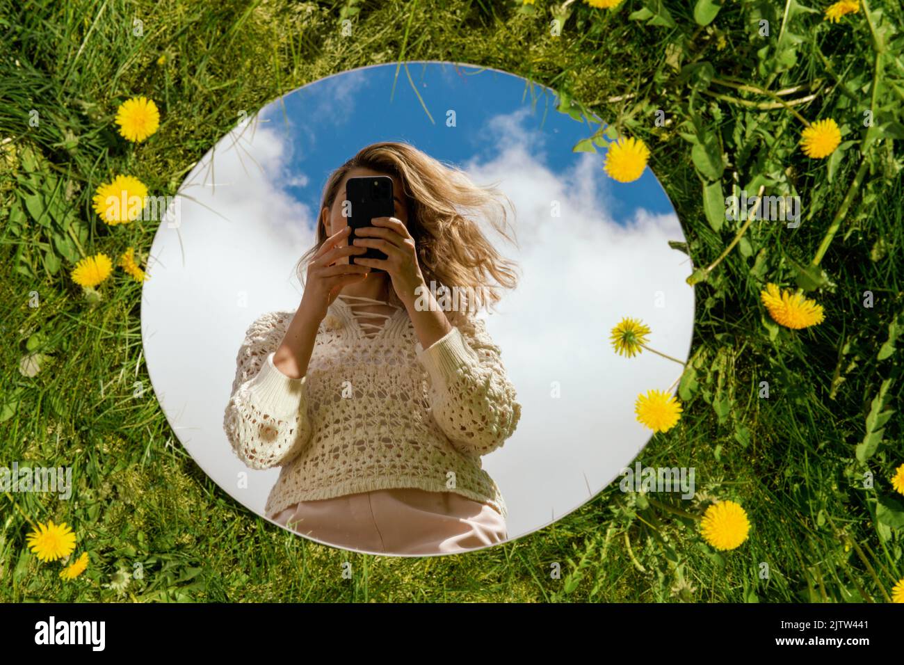 woman with smartphone reflection in round mirror Stock Photo