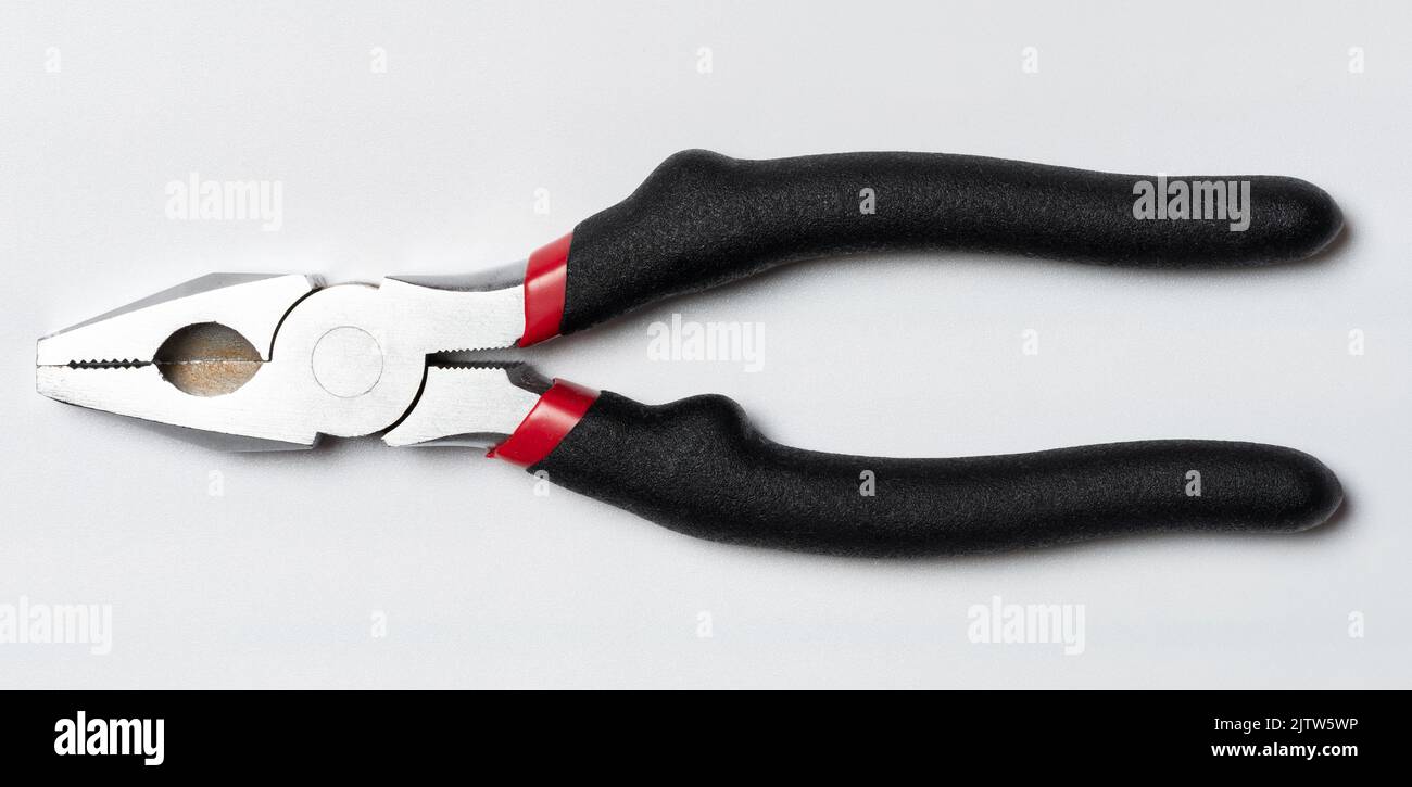 Closed metal pliers with black rubber grip isolated on studio