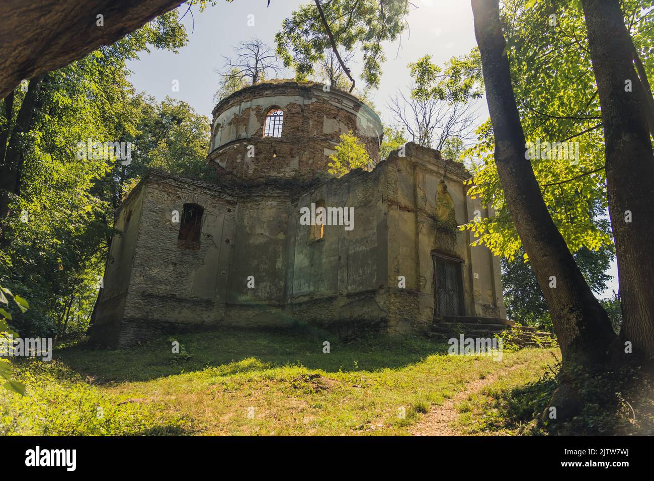 Damaged exposed brick exterior of abandoned church with tower and no roof in green forest. Old christian architecture. Lubycza Krolewska. Horizontal shot. High quality photo Stock Photo