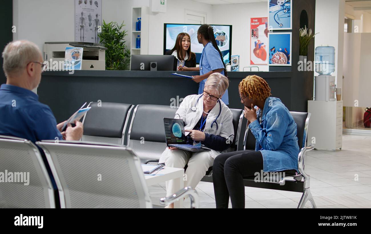 Physician showing human brain scan on laptop to young patient ...