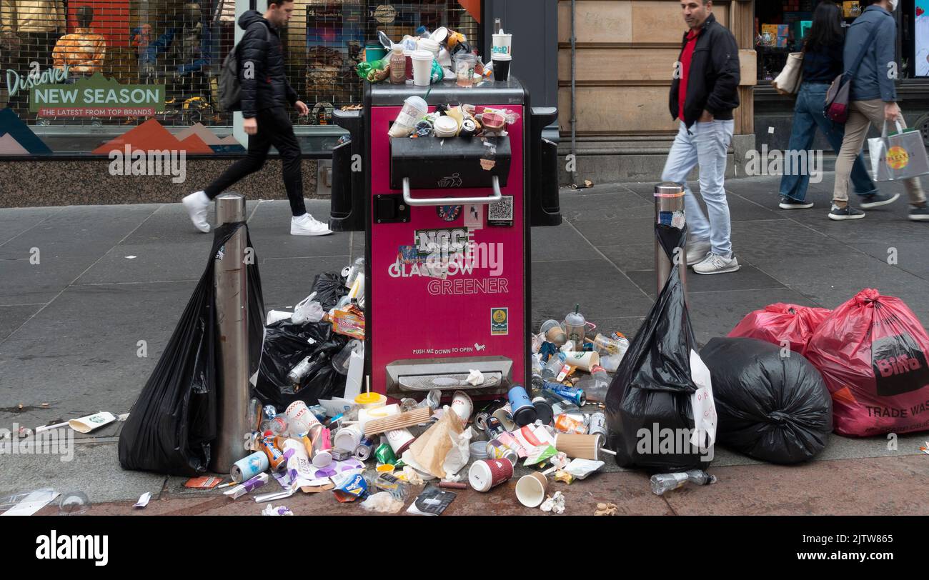 Overflowing litter bin with many full plastic bags on the pavement in Buchanan Street, central Glasgow, during a strike by Council garbage collectors Stock Photo