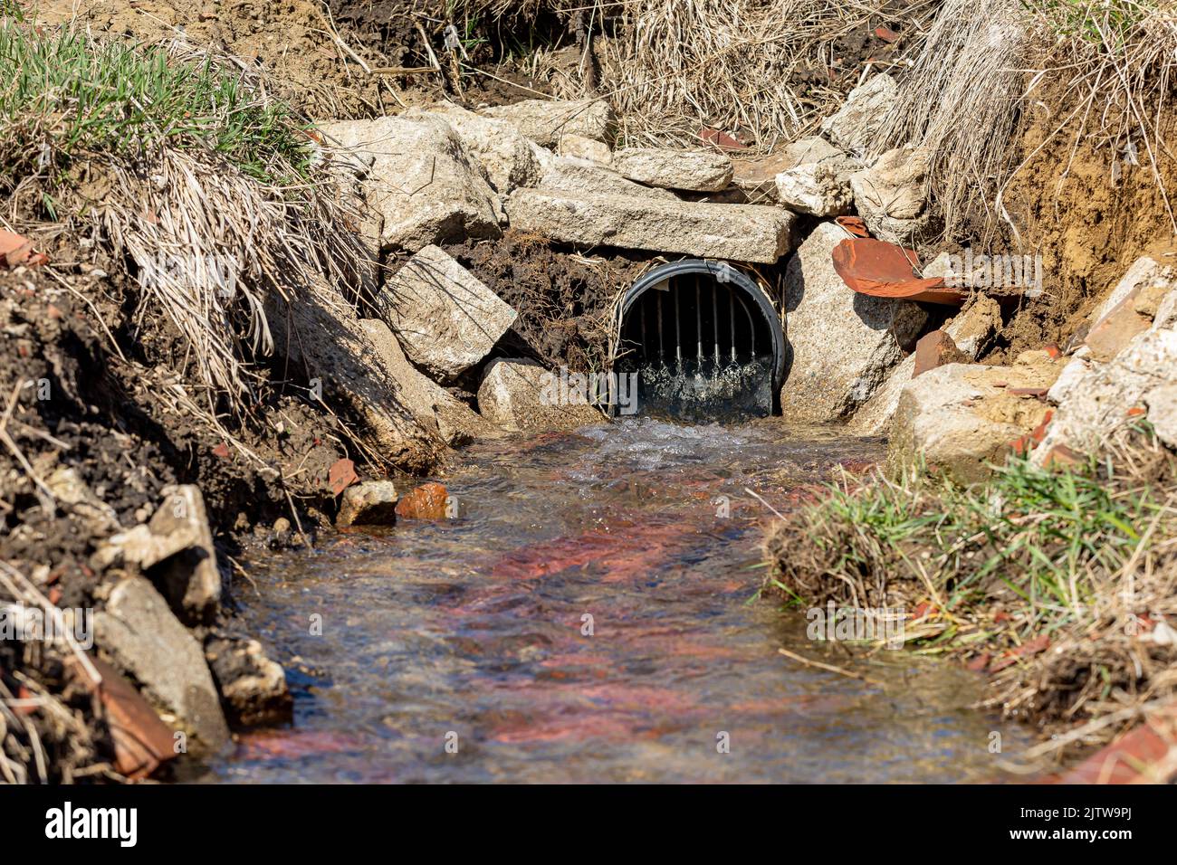Farm field tile outlet with water flowing. Water drainage, flooding control and agriculture