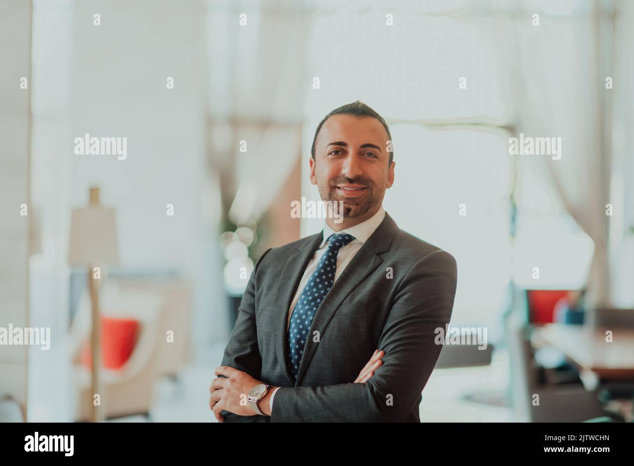 Portrait of a businessman in a suit with his arms crossed in a modern ...