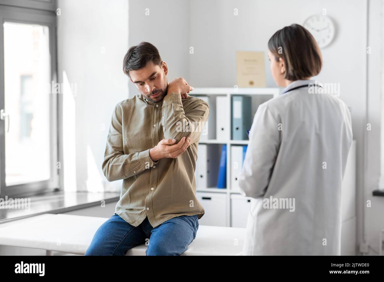 man patient showing sore arm to doctor at hospital Stock Photo Alamy