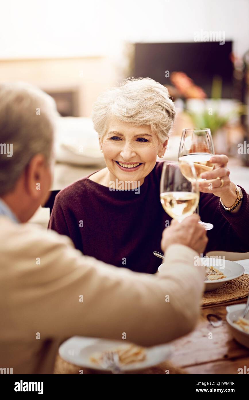 Bon appetit. an elderly couple toasting with wine glasses while they