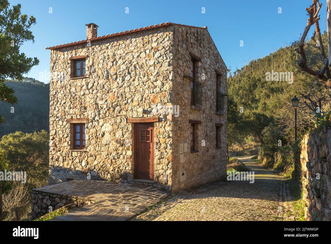 Street and stone house in the village of Casal de São Simão, Portugal, lit by the sun in the late afternoon. Stock Photo