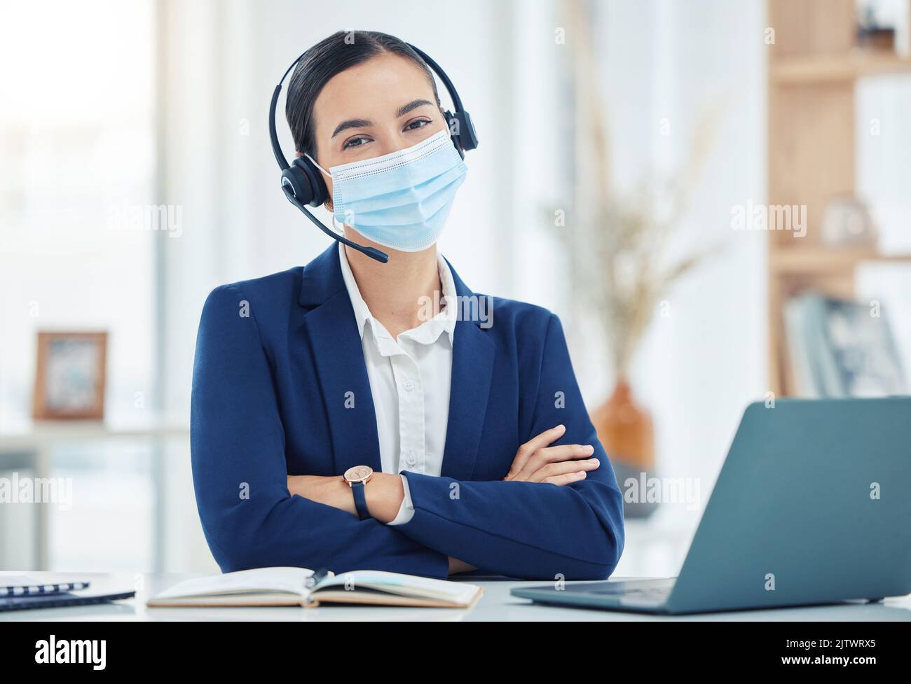 Covid, telemarketing and woman with mask portrait at a corporate work building in the pandemic. Help desk worker at table with medical face protection Stock Photo
