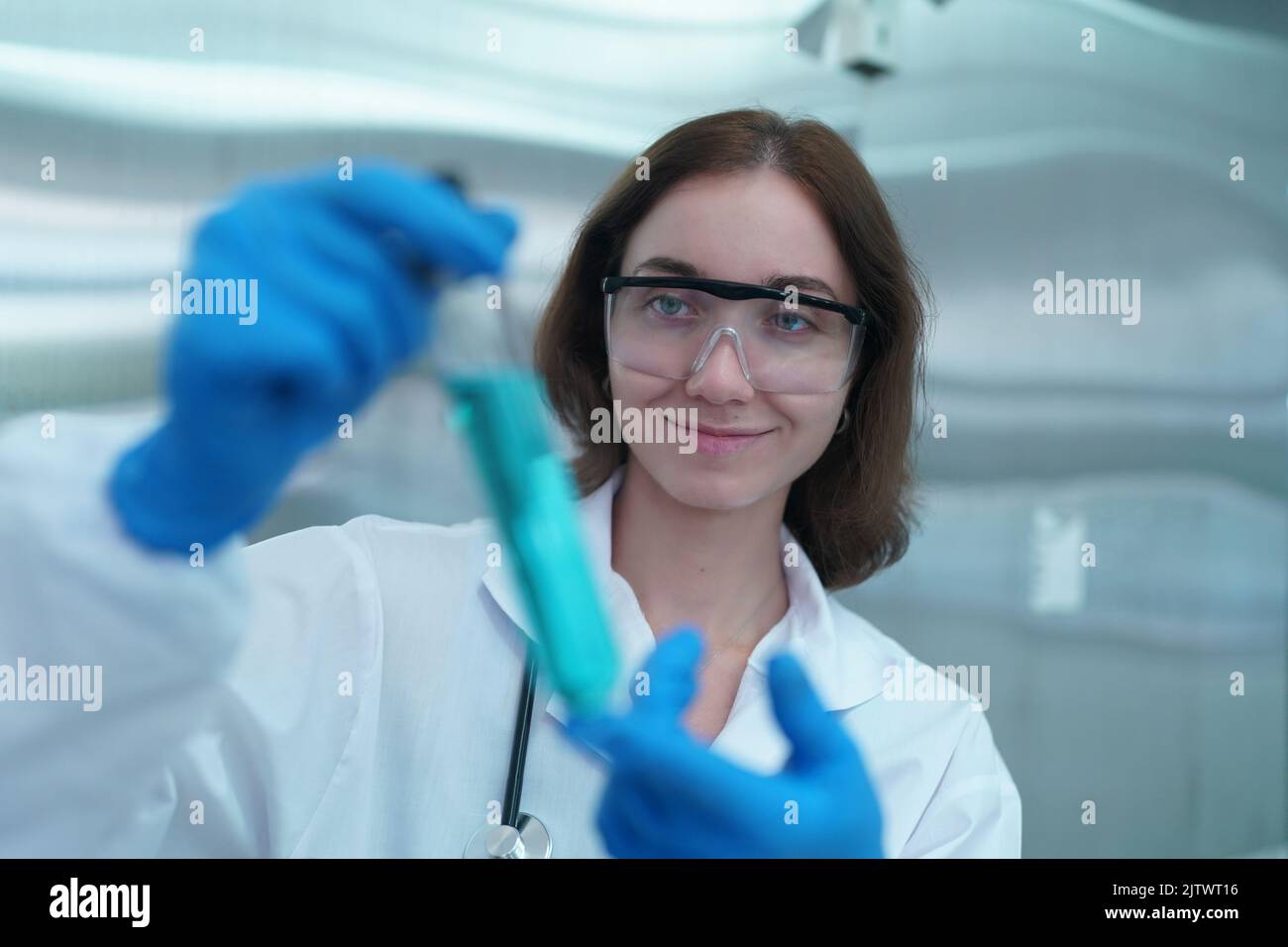 Young scientist in white lab coat working with binocular microscope in the material science lab
