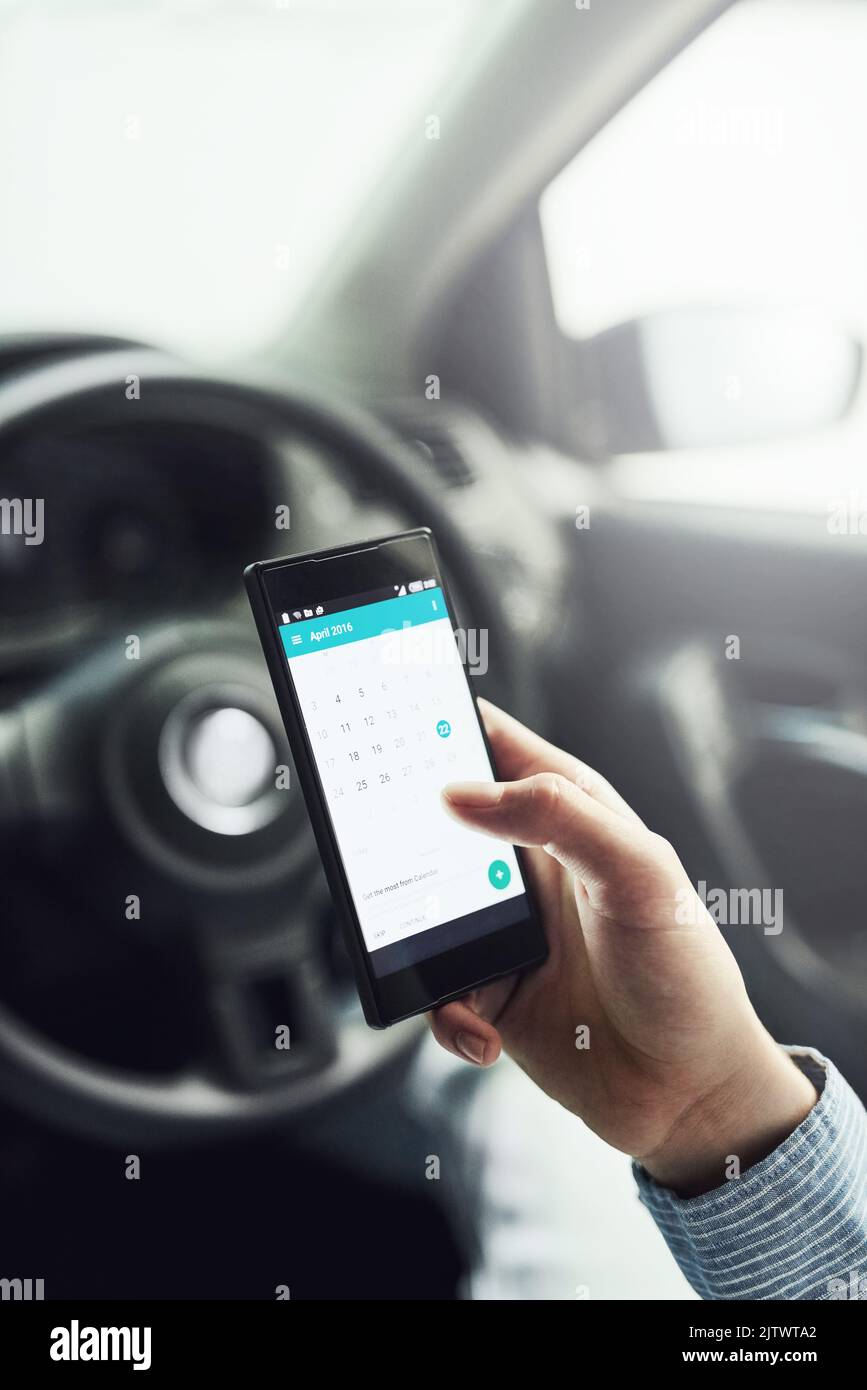 Whats on the agenda for today. Closeup shot of a driver using his cellphone in his car. Stock Photo