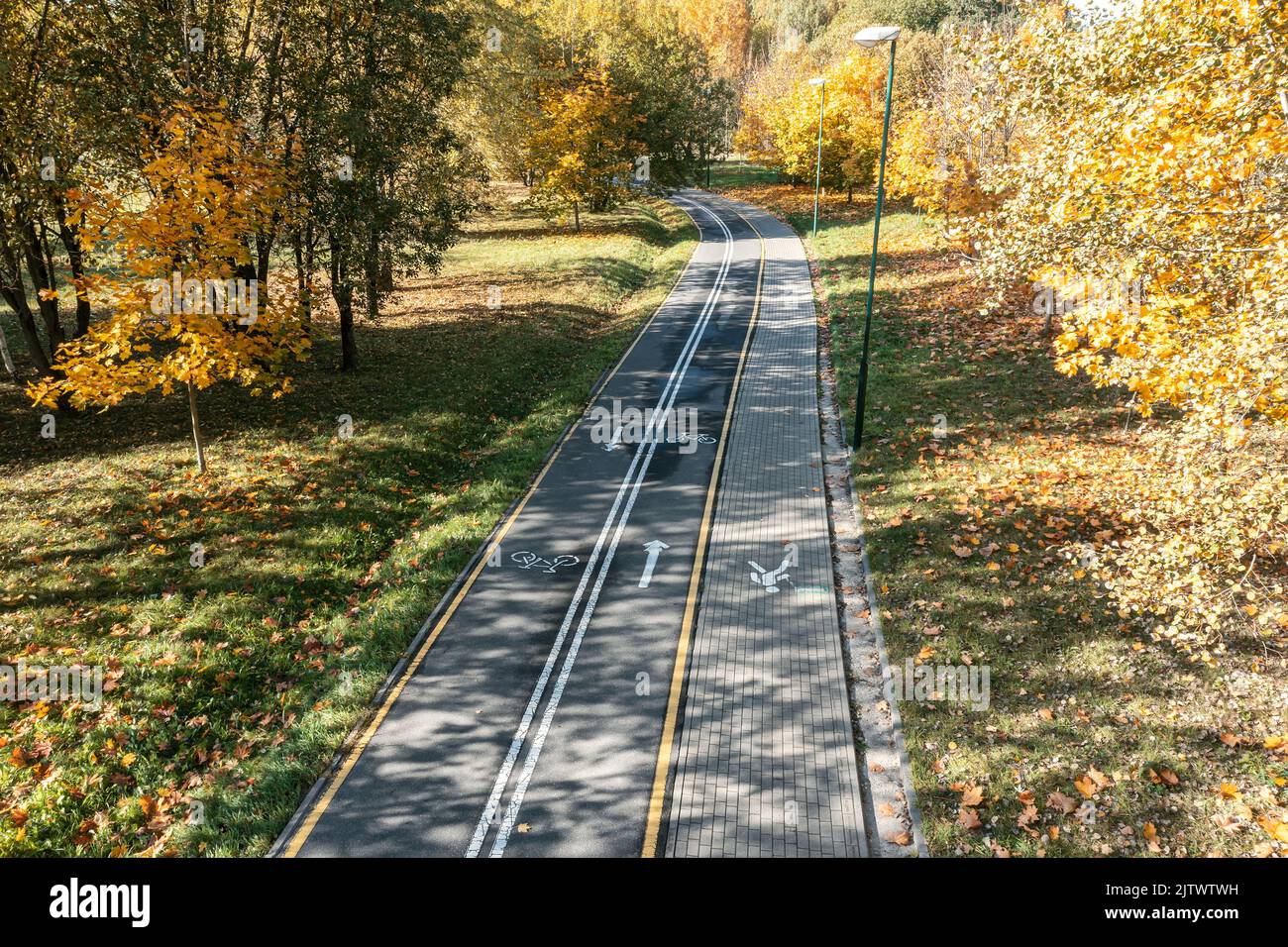 curved bike lane and pedestrian path in colorful autumn park. aerial view. Stock Photo