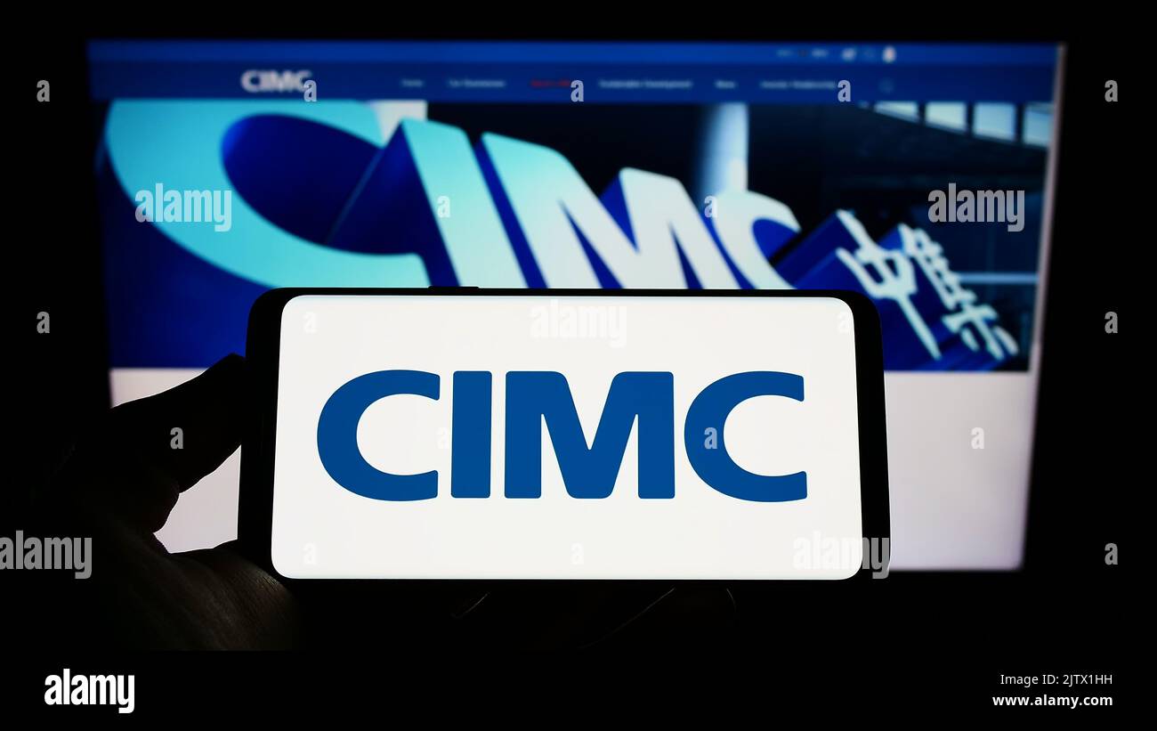 Person holding smartphone with logo of China International Marine ...