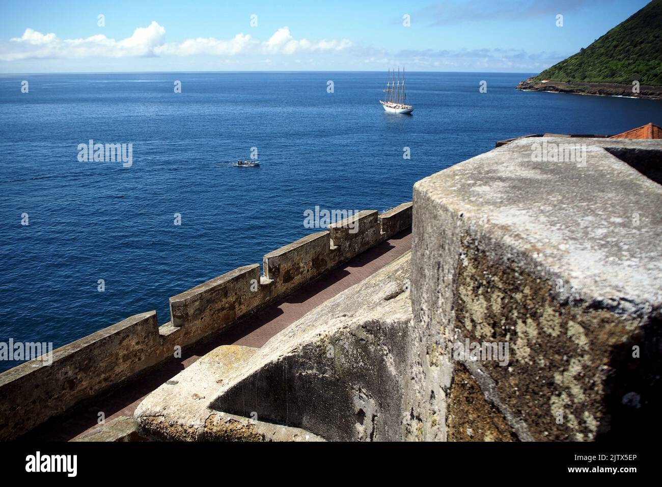 Ocean view from the Fort of Sao Sebastiao, part of the corner bastion, tall ship anchored offshore, Angra do Heroismo, Terceira, Portugal Stock Photo