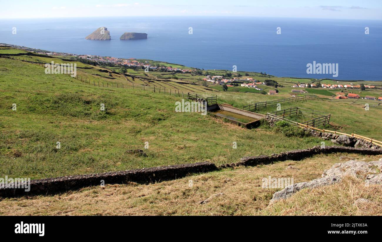 Rural landscape, green pastures and stone fences, sloping toward the ocean coast, Cabras Islets off shore, Terceira, Azores, Portugal Stock Photo