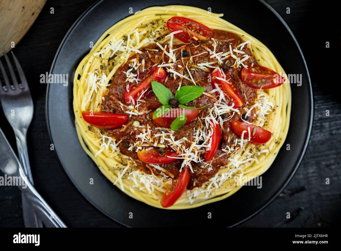 Italian spaghetti pasta with tomato sauce, parmesan cheese and basil served on the plate on rustic kitchen table. Flat lay. Top view. Stock Photo