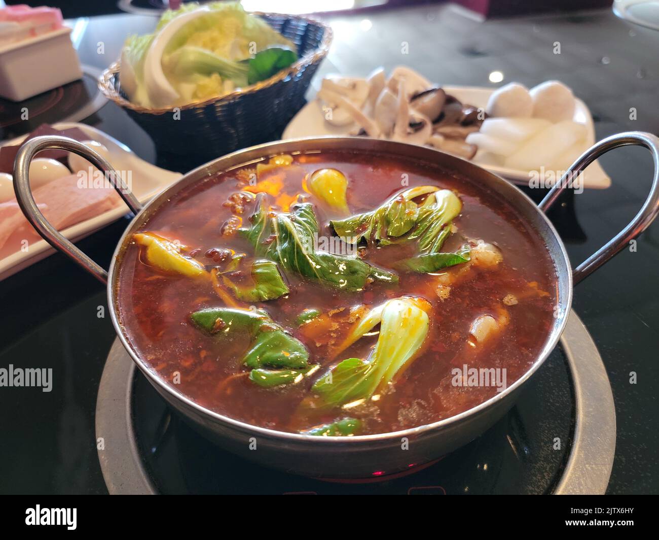 spicy Chinese hot pot with cabbage pork fish and eggs on table Stock