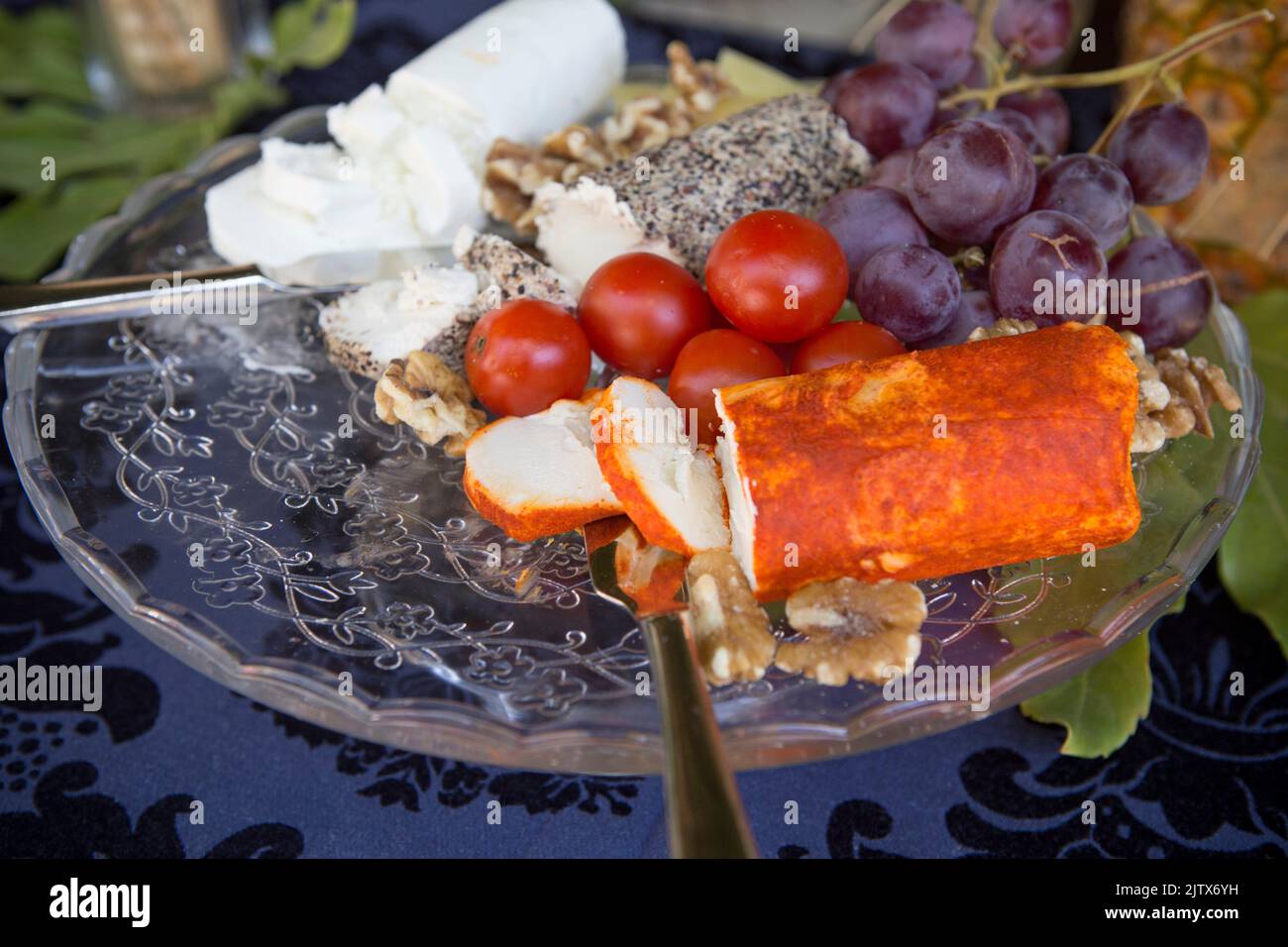 Glass tray full of Goat cheese rollers with grapes and cherry tomatoes. Selective focus. Stock Photo