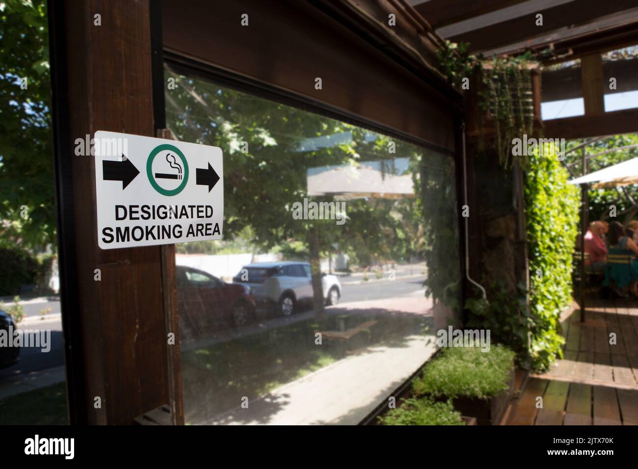 Designated smoking area sign pointing to open garden area. Hotel smoking policies concept. Stock Photo