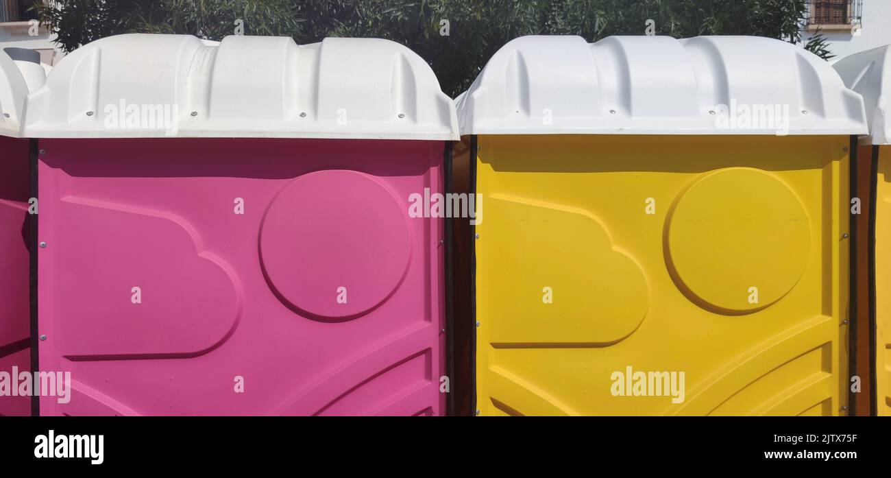 Pink and yellow portable toilets. Outdoors shot. Stock Photo