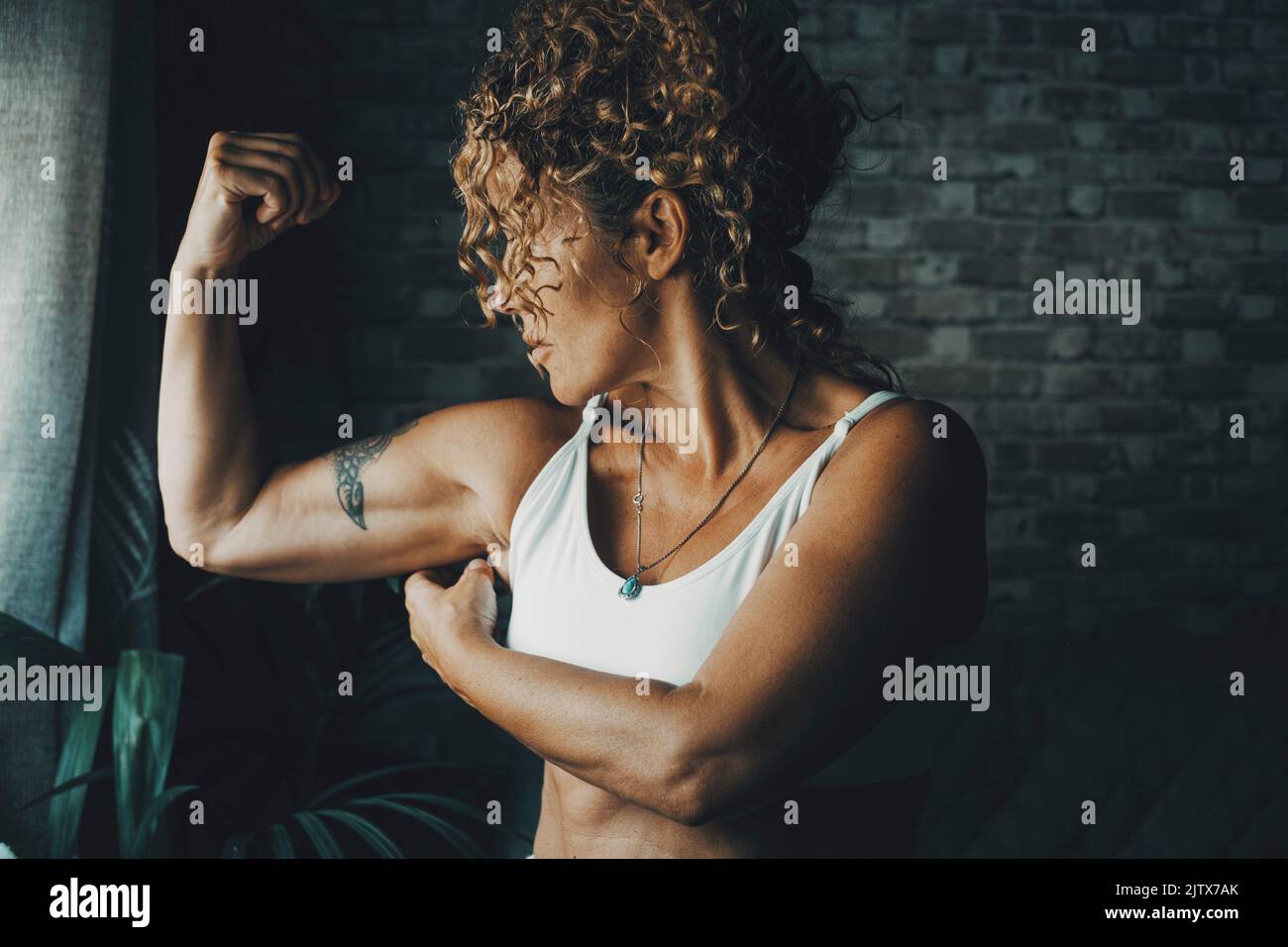One middle age 50s woman at home doing biceps muscle. Concept of energy and power lady doing sport activity and fitness workout. Healthy body Stock Photo