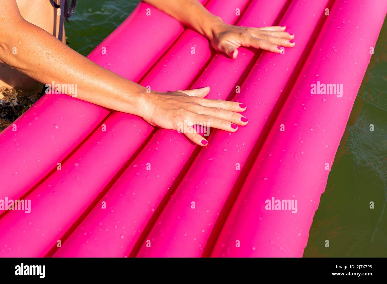 woman holding pink inflatable mattress in sea water. Stock Photo