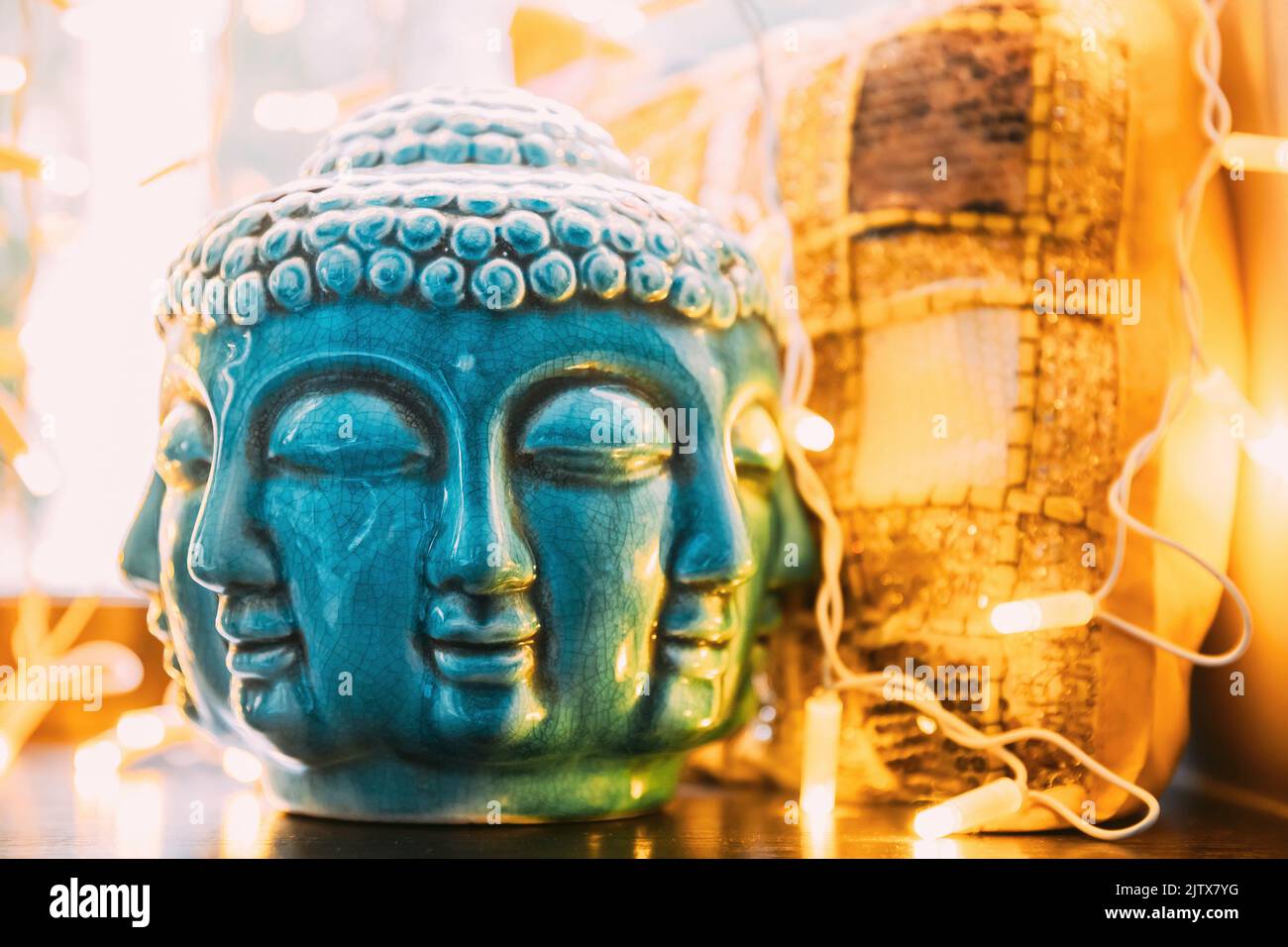 Blue statue of Buddha head lighted by bokeh boke lights. Interior element. Stock Photo