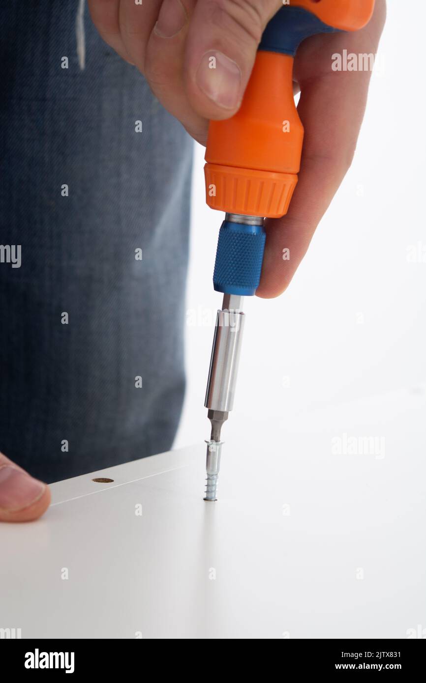 Man hand screwing the screws into furniture. Assembling furniture at home Stock Photo