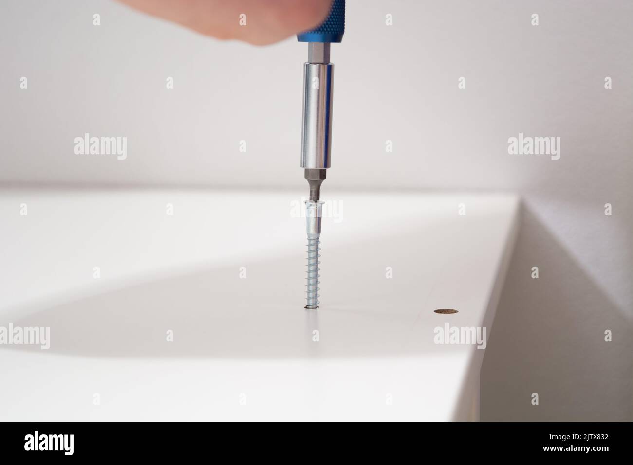 Man hand screwing the screws into furniture. Assembling furniture at home Stock Photo