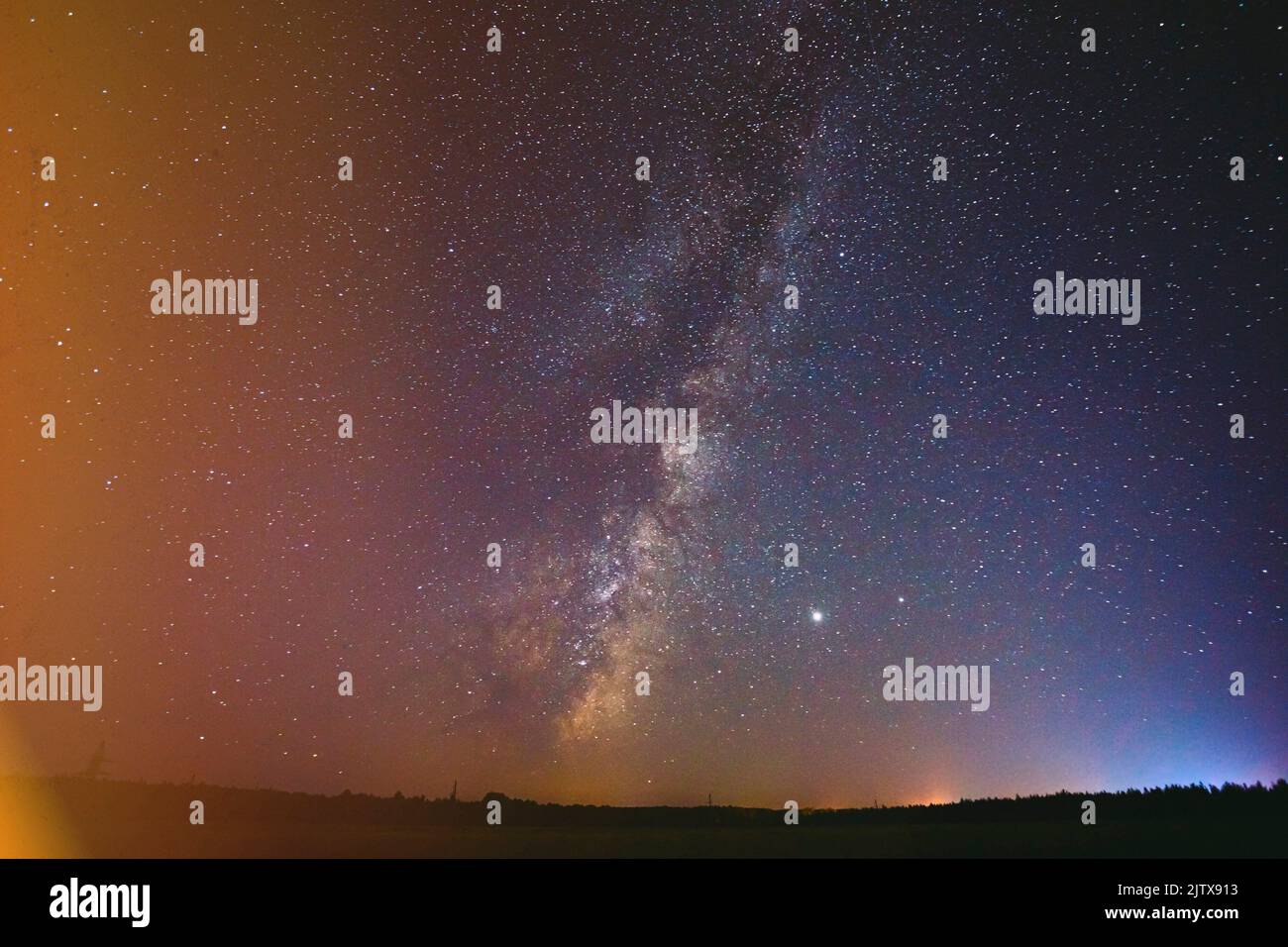 milky way above dark landscape. Colorful flare flash haze on starry sky. Sky Stars. Starry Sky Background Backdrop. Stock Photo