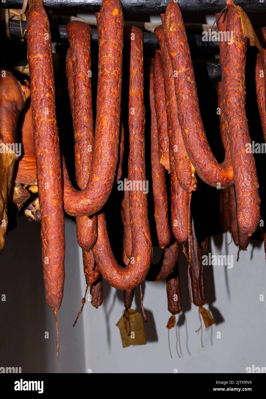 Smoked, dry, cured sausages hanging in the vintage smokehouse. Stock Photo