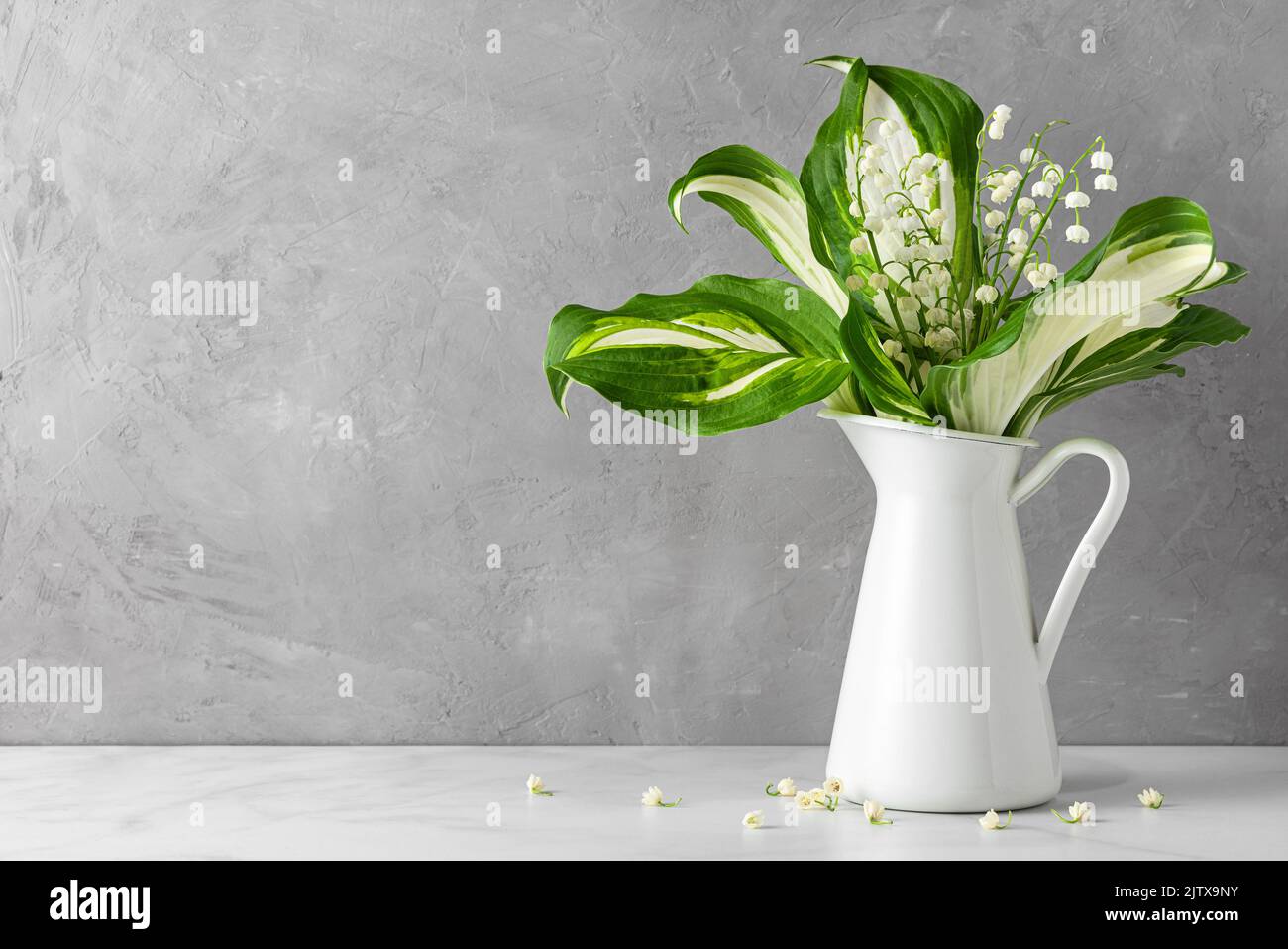 Lily of the valley flowers bouquet in vase on gray concrete background. womans day or wedding background with copy space Stock Photo