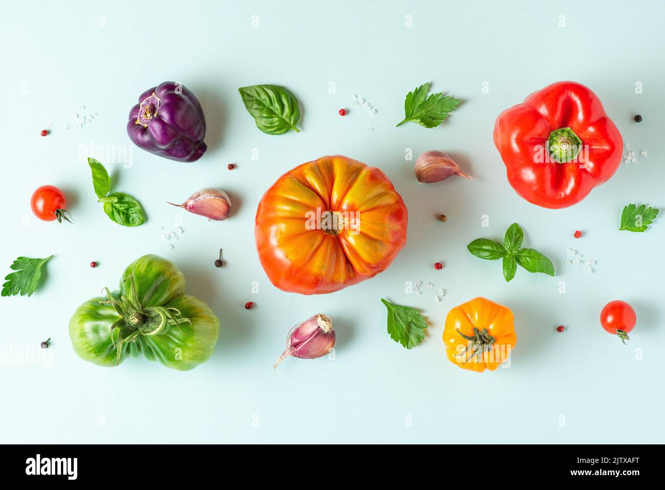 Creative layout made of tomatoes, pepper, garlic, basil leaves. Flat lay. Top view. Food composition. Vegetables on blue background. Food ingredient p Stock Photo