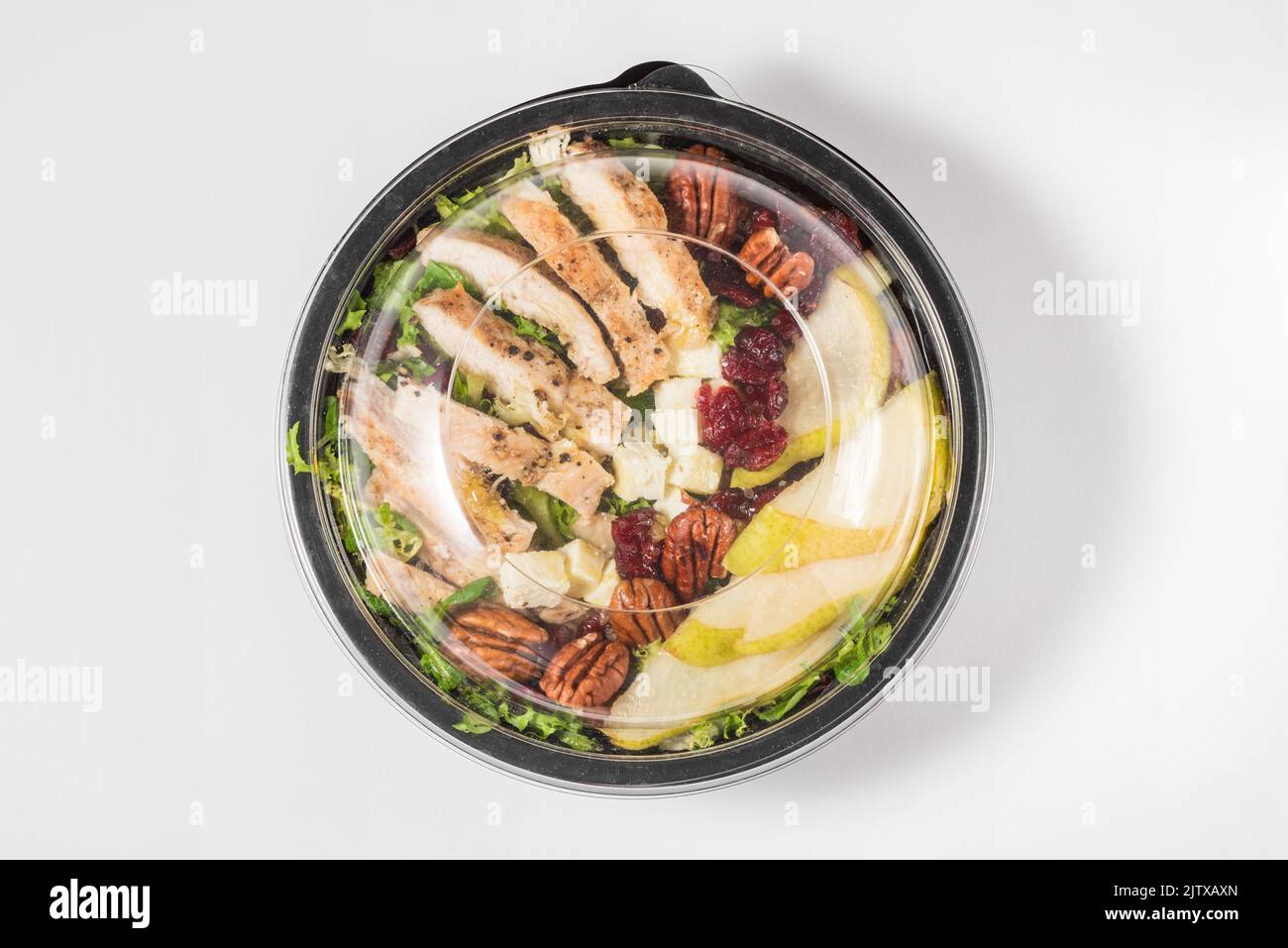 Plastic package with healthy chicken and pear salad for take away or food delivery on white background. Top view. Food in lunch box Stock Photo