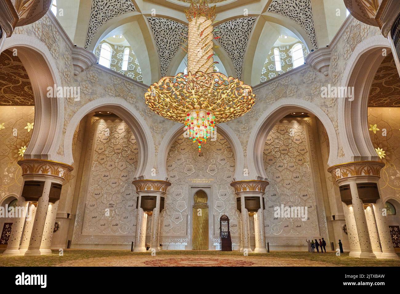 Tourists visiting the prayer room at Sheikh Zayed Mosque.A very large chandelier hung from the ceiling. Abu Dhabi. United Arab Emirates. Stock Photo