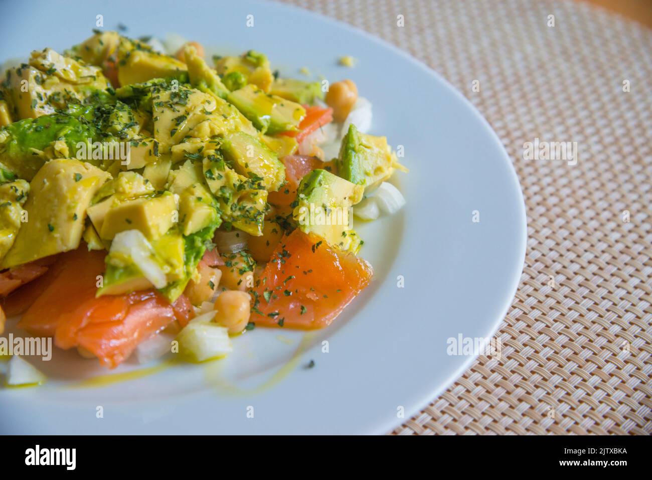 Salad made of avocado, tomato, chickpeas, onion, coriander and olive oil. Stock Photo