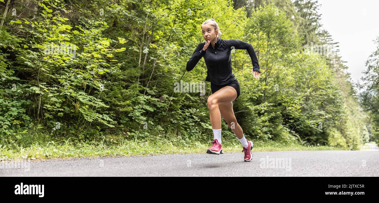 Dedicated sprinter runs on an asphalt road outdoors training for better performance. Stock Photo