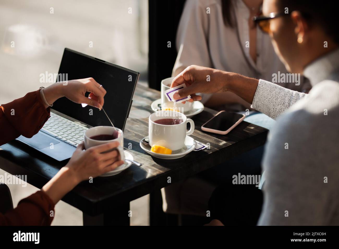 Three friends in a restaurant talking and having tea. Business colleagues in a meeting after work or during coffee break at a cafe bar. Abstract photo Stock Photo