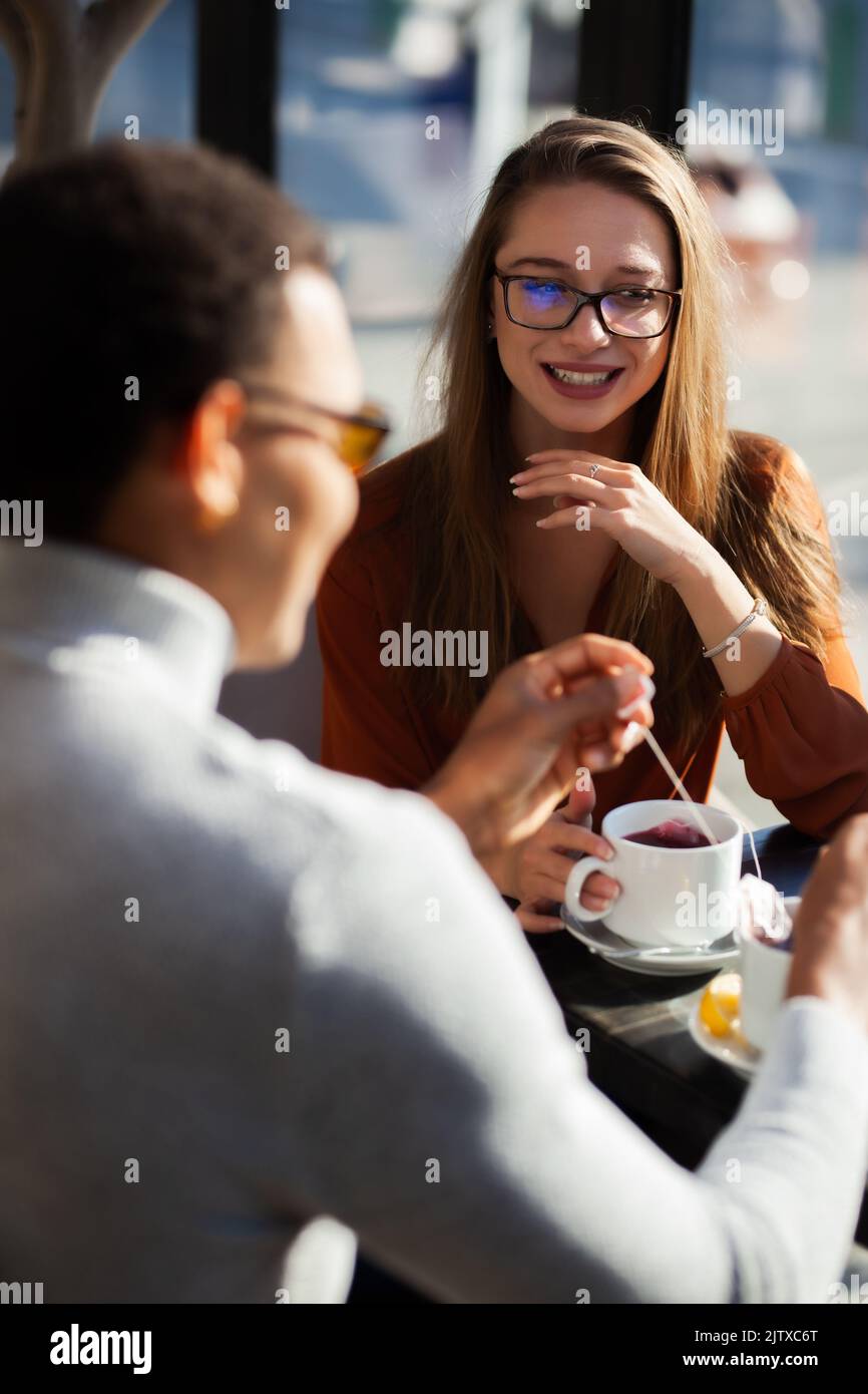 Friends in a restaurant talking smiling and drinking tea. Business colleagues having a meeting after work or during coffee break at a cafe bar. Stock Photo