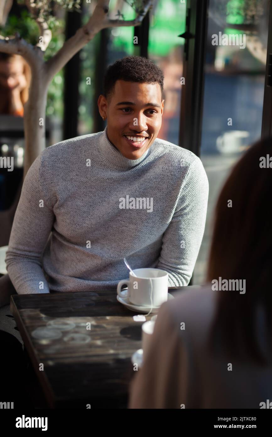 Two friends in a restaurant talking smiling and drinking tea. Multuracial business colleagues having a meeting after work or during coffee break at a Stock Photo