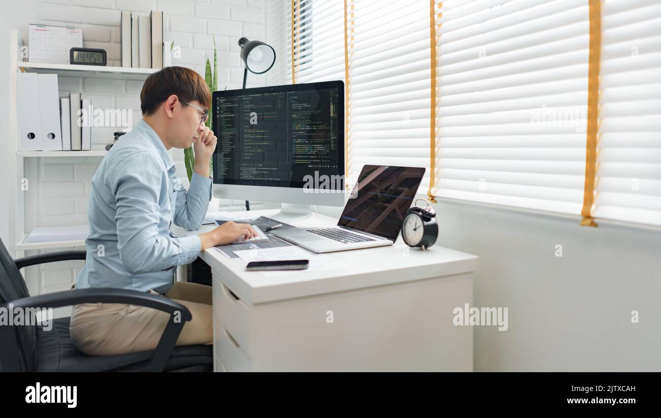 Software development concept, Male programmer looking data on laptop and typing codes on keyboard. Stock Photo